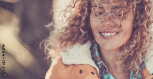 Happy woman with closed eyes feeling satisfied or content. Female traveler in curly hairstyle and fur jacket with her eyes closed in thoughts. Thoughtful woman smiling