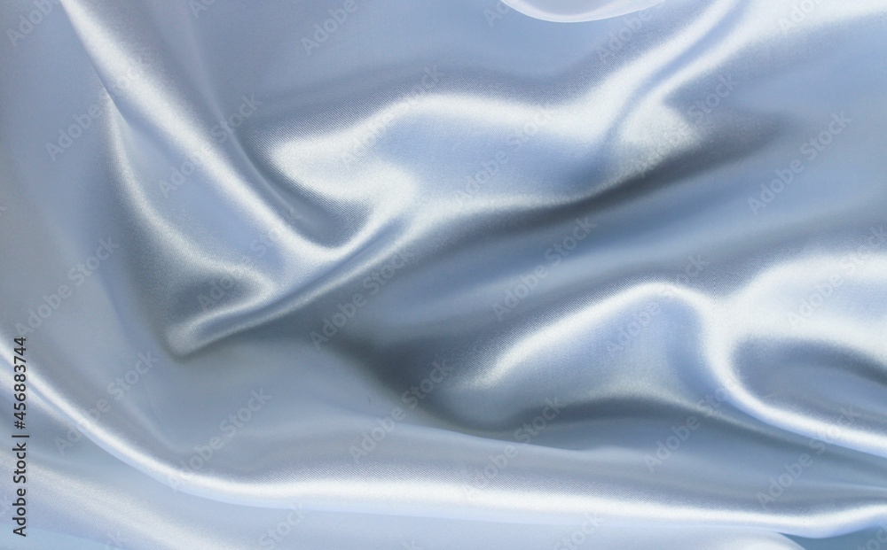 Obraz premium Delicate pearl white fabric with beautiful pleats. Silk, satin are folded freely. It can serve as a background for the inscription. Pastel shades.
