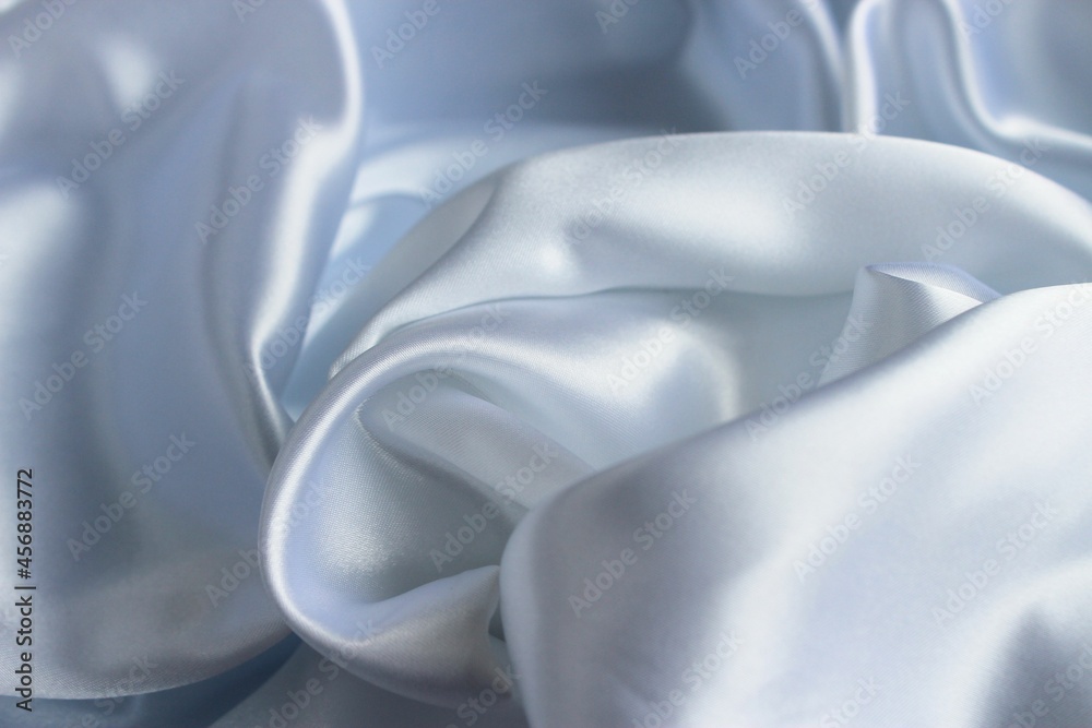Obraz premium Delicate pearl white fabric with beautiful pleats. Silk, satin are folded freely. It can serve as a background for the inscription. Pastel shades.
