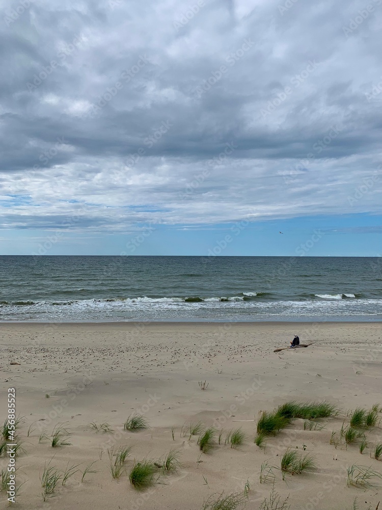 Lonely human silhouette at the wild empty beach, sea view background