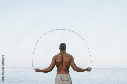 Fit man jumping rope at the beach photo