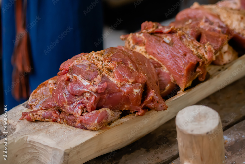 Freshly juicy marinated meat with spices and onion on wooden board at summer local food market - close up view. Outdoor cooking, gastronomy, cookery, street food concept
