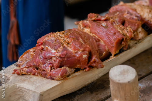 Freshly juicy marinated meat with spices and onion on wooden board at summer local food market - close up view. Outdoor cooking, gastronomy, cookery, street food concept