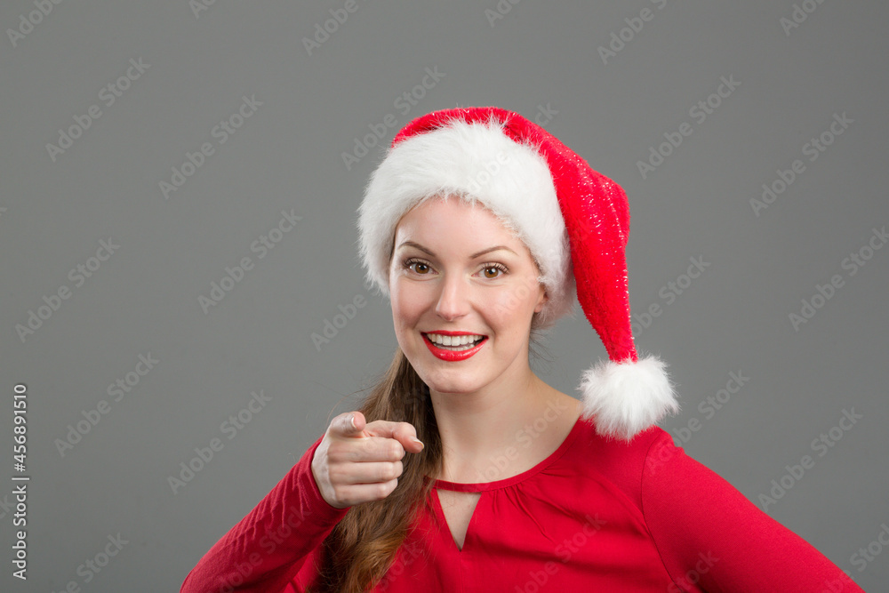 young woman with santa claus hat is pointing