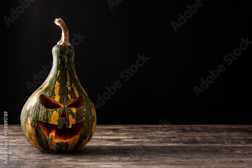 Halloween green pumpkin on wooden table and black background. Copy space