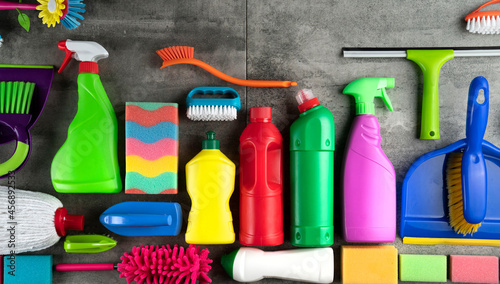 Autumn cleaning. Colorful set of bottles with clining liquids and colorful cleaning kit on gray tiles.