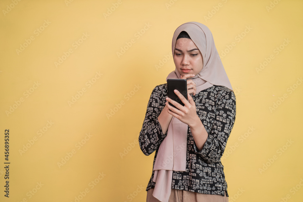 Obraz premium veiled woman looking at screen while using a smartphone with worried expression with copyspace