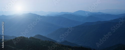 Panorama of dark blue mountain landscape in fog. Horizontal image. © zwiebackesser