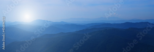 Panorama of beautiful dark blue mountain landscape in fog. Horizontal image.