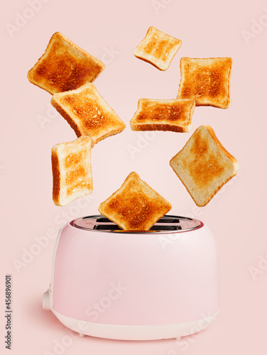 A toaster with loaves of toasted bread flying in the air isolated on a pastel pink background. Morning ingredient, diet and nutrition idea. Creative food concept. Surreal diet backdrop.