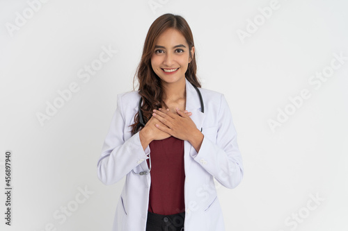 beautiful doctor in white uniform holding chest and smiling with patient expression