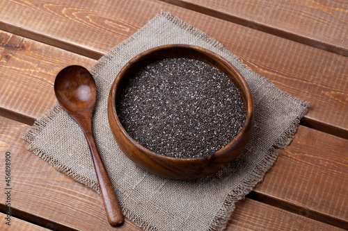 Chia seeds in a bowl with a wooden spoon on a natural wooden background. Rustic style. photo