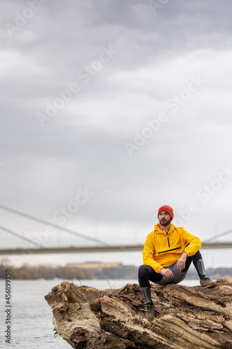 Man taking a jogging break sitting by the river