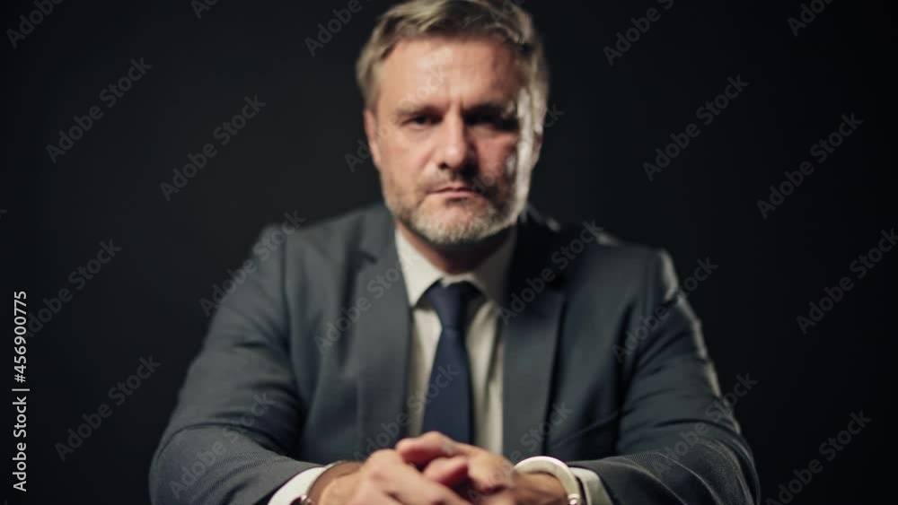 Portrait of a criminal in business suit handcuffed in interrogation room, fraud Portrait of a criminal in business suit handcuffed in interrogation room, fraud