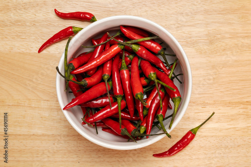 Red chili pepper in a bowl on a wooden surface