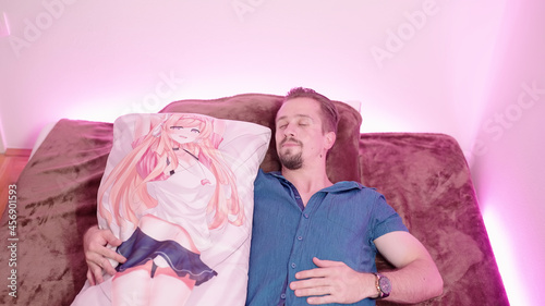 Man sleeping with 2D anime girl waifu dakimakura body pillow on bed photo