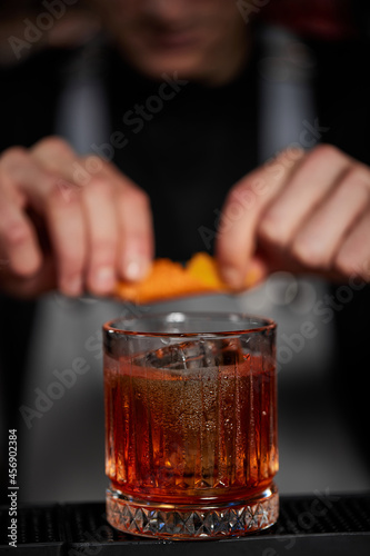 Fotografija bartender makes a cocktail in a glass with orange peel