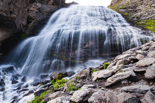 A giant mountain waterfall on a sunny summer day  streams of water fall from a great height on rocky rocks