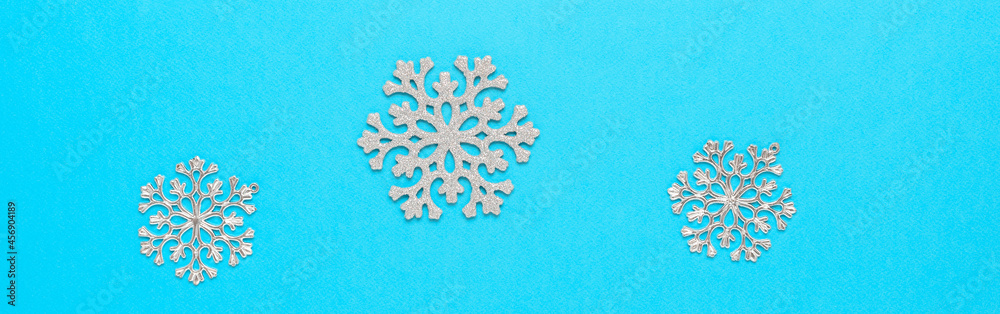Beautiful Christmas border with silver snowflakes on blue paper background. Top view, flat lay. Beautiful Christmas border with silver snowflakes on blue paper background. Top view, flat lay.
