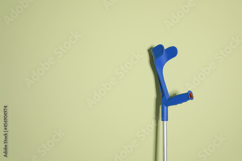 Elbow crutch on light green background. Space for text photo