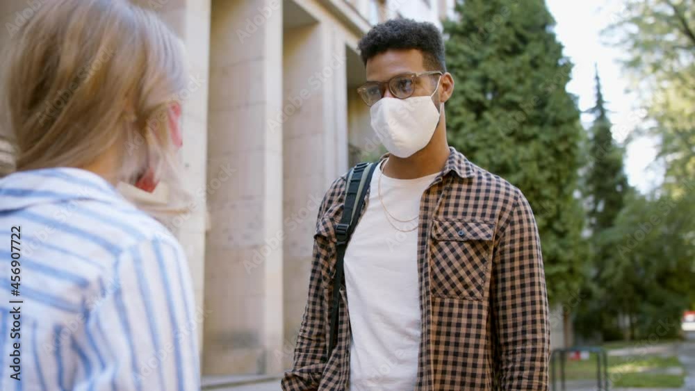 Two students meet in front of the university building. Coronavirus conept.