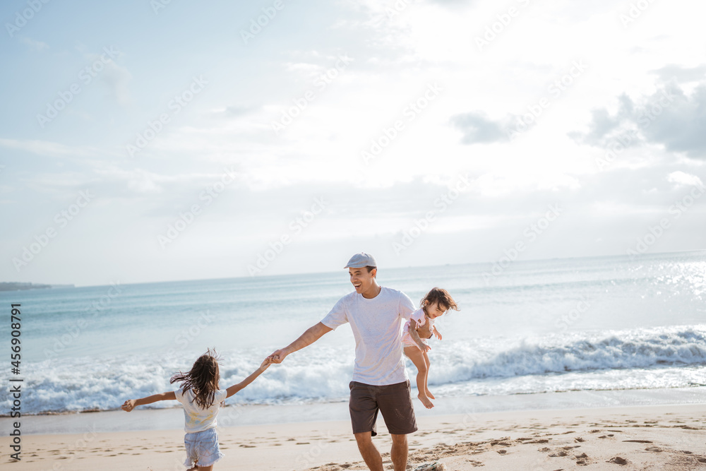 Dad playing with his daughter on the beach having fun together