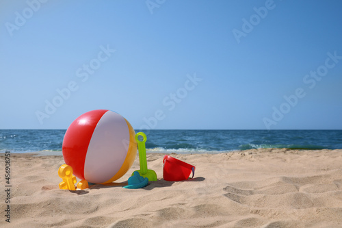 Many different sand toys and beach ball near sea, space for text
