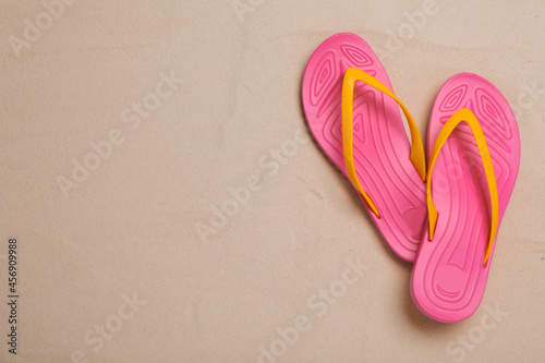 Pair of pink flip flops on sand, flat lay. Space for text