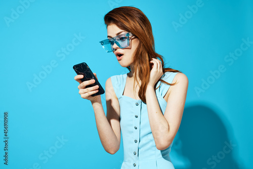 pretty woman in a dress and glasses with phone in hand isolated background