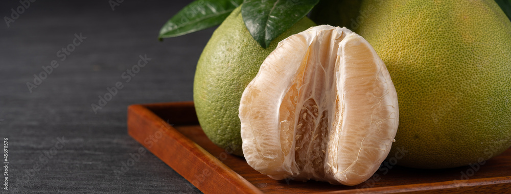 Fresh pomelo fruit on black slate background.