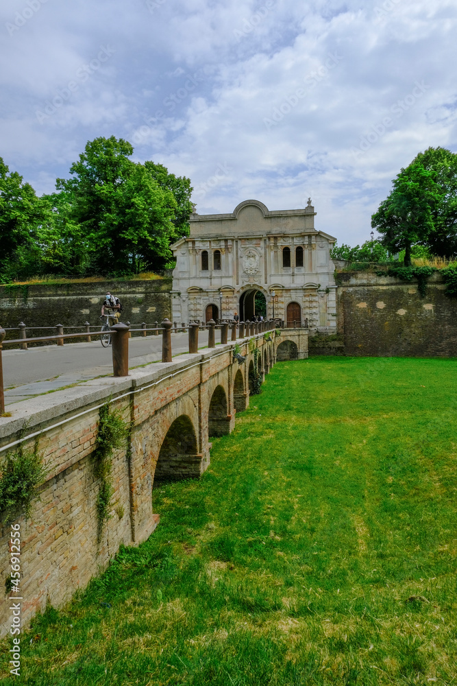 Parma, Italy: Entrance-fortress of Cittadella park, a bridge over the meadow, and its visitors on sunny day