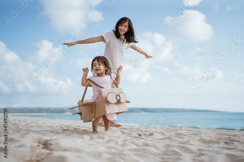 lovely mother and daughter playing with airplane cardboard toy