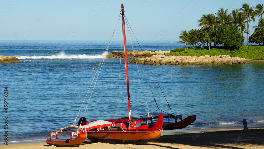 Obraz premium Outrigger boat on the beach next to a lagoon in Hawaii.