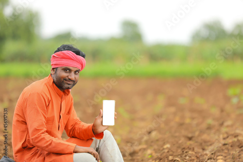 technology concept : Young indian farmer showing smartphone. photo