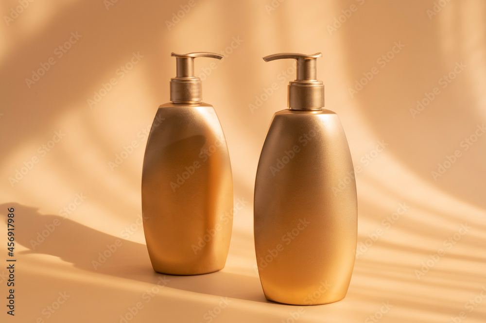 Golden clean bottles of cosmetics with sun shadows on beige background. Cosmetic mock up bottles, tubes. Branding products, spa, beauty background. Flat lay top view copy space. Place you design Golden clean bottles of cosmetics with sun shadows on beige background. Cosmetic mock up bottles, tubes. Branding products, spa, beauty background. Flat lay top view copy space. Place you design
