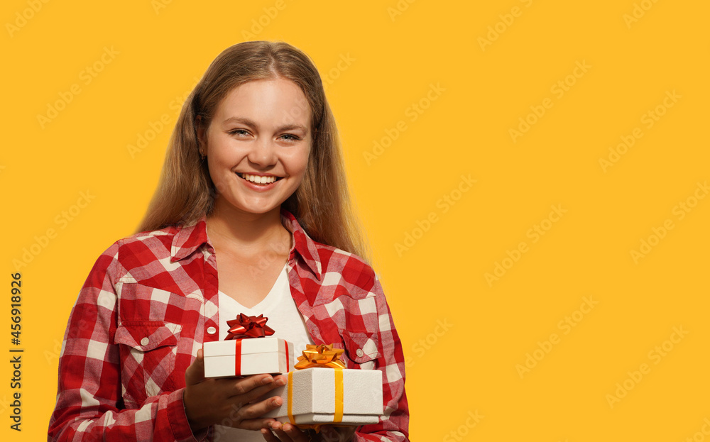 Smiling beautiful blonde young woman holding a gift boxes isolated over yellow background. Happy birthday, Christmas, Valentine's Day concept. Place for text. Smiling beautiful blonde young woman holding a gift boxes isolated over yellow background. Happy birthday, Christmas, Valentine's Day concept. Place for text.