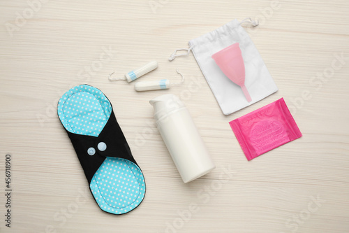 Cloth menstrual pad and other female hygiene products on white wooden table, flat lay