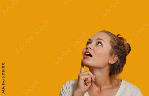 Portrait for advertisement of surprised shocked young blonde woman looking with eyes at empty place having wide open mouth eyes isolated on yellow background.