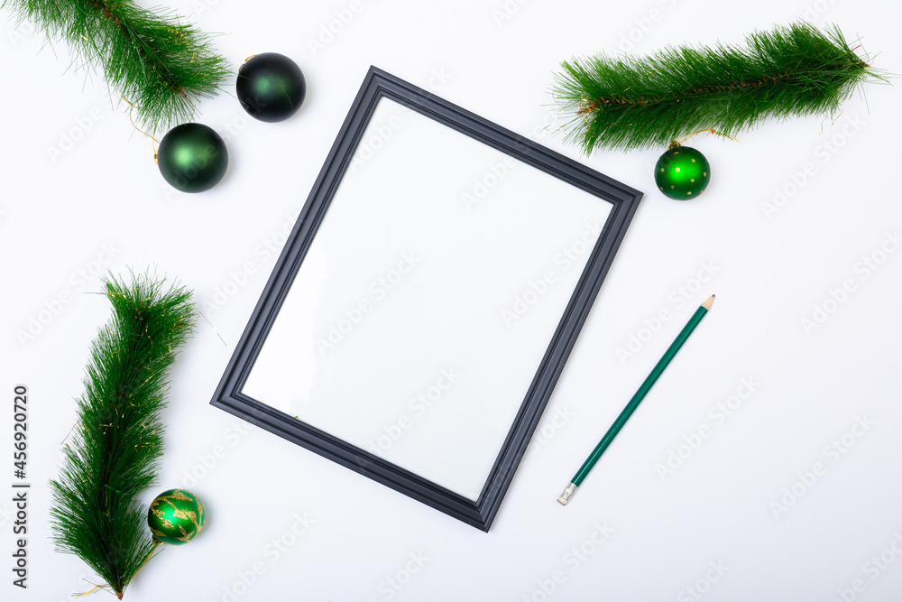 Fototapeta premium Composition of frame with copy space and fir tree branches with baubles on white background