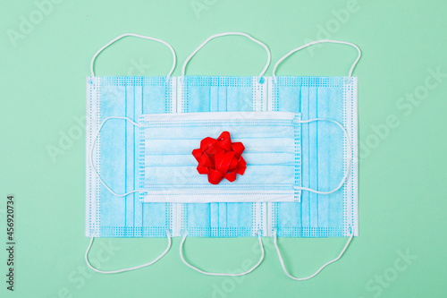 Composition of face masks with red ribbon on green background