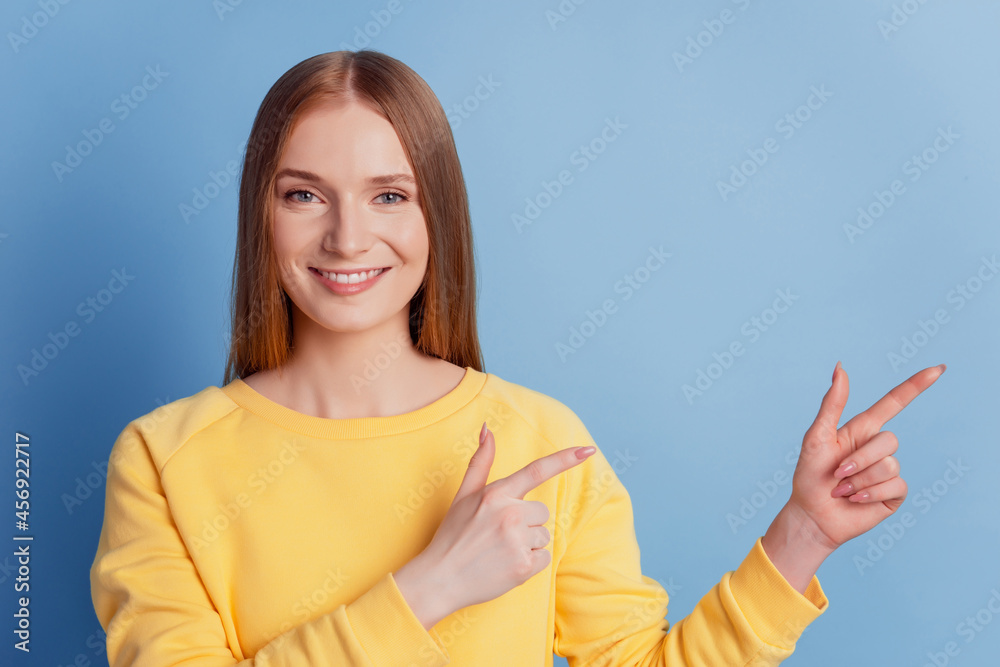Portrait of readhead charming girl direct fingers empty space on blue background Portrait of readhead charming girl direct fingers empty space on blue background