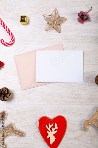 Composition of white card with copy space, envelope and christmas decorations on wooden background
