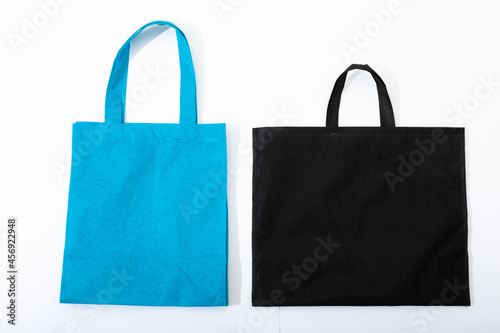 Composition of empty blue and black canvas shopping bags lying flat on white background