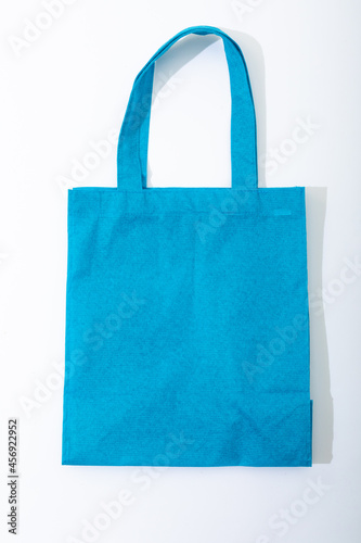Composition of empty blue canvas shopping bag lying flat on white background