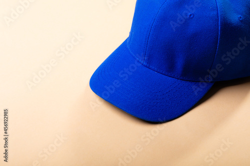 Composition of traditional peaked blue baseball cap on pale brown background photo