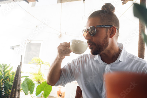 Mężczyzna pijący kawę w kawiarni w słoneczny dzień.
