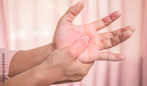 Closeup of female holding her painful palm and numbness caused by prolonged work on the computer or housewife, Carpal tunnel syndrome, arthritis. Neurological disease concept. photo