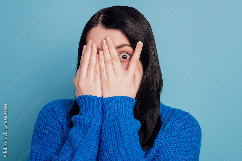 Portrait of nice young person arms palms covering face eye fear horror isolated on blue color background Portrait of nice young person arms palms covering face eye fear horror isolated on blue color background