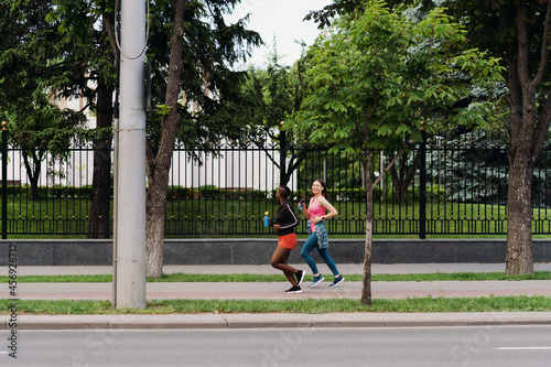 Good riends in sportswear running in the city dicussing. Multiethnic women having a fitness workout. photo