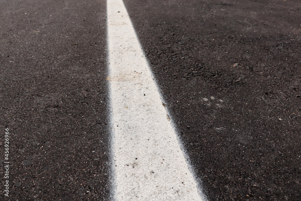Asphalt track just made with some dirt and its texture, with a white strip painted in the center of the image